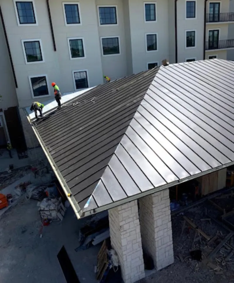 Crew installing standing seam metal roof panels on a commercial project in Belvidere